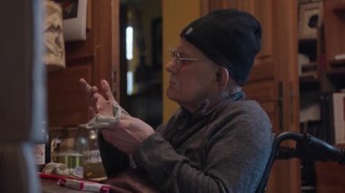 Tekerlekli sandalyedeki kıdemli ressam bir stüdyoda tuvale yağlı boya bir resim çizer.