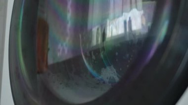 Bulutlu bir günde banyoda pencerenin önünde çamaşır makinesi çalışıyor.