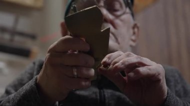 Tekerlekli sandalyedeki yaşlı erkek usta atölyesinde mobilyaları restore ediyor.