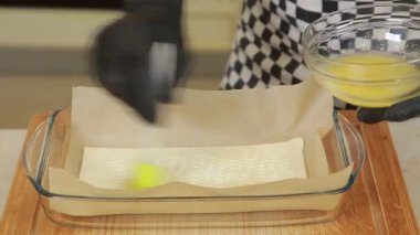 Ekşi krema, yumurta, puf böreği, zeytin yağı, ıspanak yaprakları ve cam bir fırında ev yapımı ıspanak güveci hazırlamak ve pişirmek için adım adım kullanılan diğer malzemeler. Ev yemeği pişirme, yemek hazırlama aşamaları ve fırın pişirme konsepti