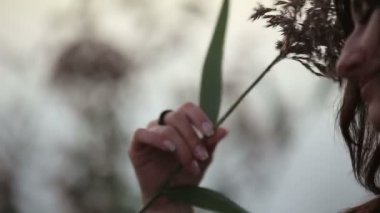 Bir genç çok esmer gündoğumu göl üzerinde izlerken çim ile oynamaktan yakın çekim