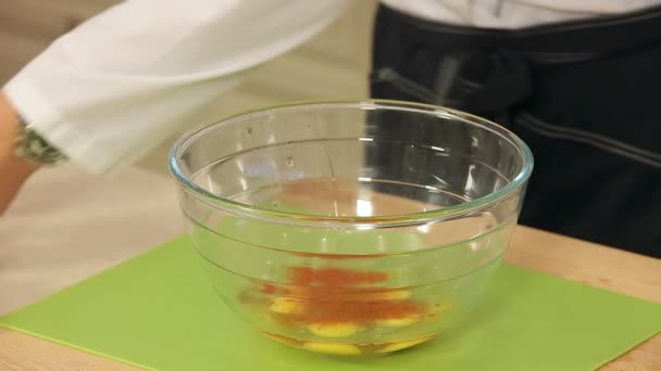 Chef está mezclando sal y especias con huevos de pollo en un tazón de cristal — Vídeos de Stock