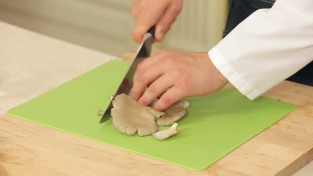 Chef sta affettando funghi marroni su un tagliere in una cucina — Video Stock