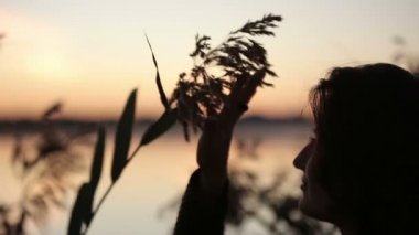 Göl üzerinde gündoğumu izlerken çim ile oynarken esmer genç güzel