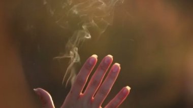Genç esmer sisli gündoğumu sırasında ellerini duman oynamaktan