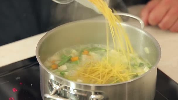 Chef está poniendo pasta en una olla hirviendo de sopa de verduras — Vídeo de stock