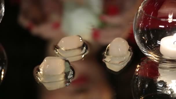 Hermosa morena en vestido rojo jugando con una vela y fusión de cubitos de hielo en la mesa del espejo — Vídeos de Stock