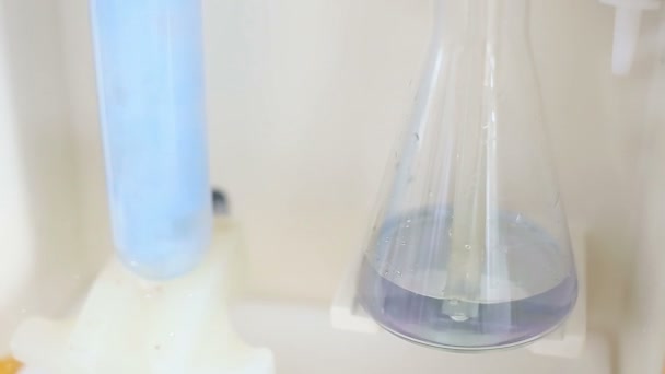 Glass in a chemical laboratory, colored liquid during the reaction — Stock Video