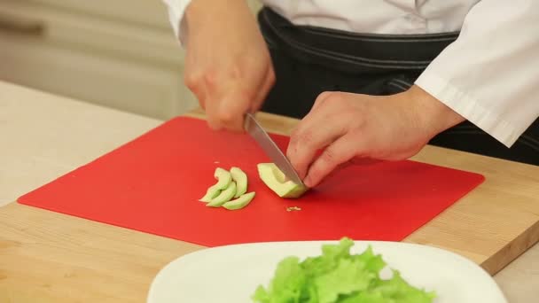 Chef-kok segmenteringshulplijnen avocado voor salade — Stockvideo