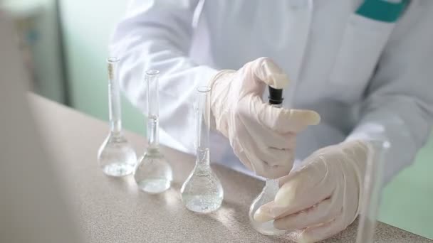 Onderzoeker werkt met vloeistoffen in chemisch laboratorium — Stockvideo