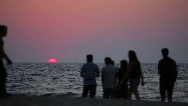 Menschen ruhen sich bei Sonnenuntergang am Strand aus — Stockvideo