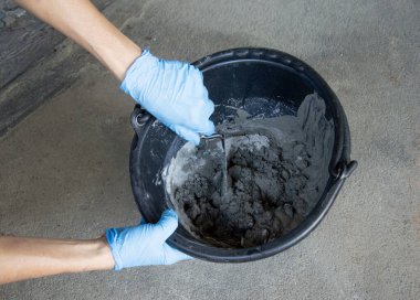 İnşaat işçileri bir kovada çimento karıştırıyorlar..