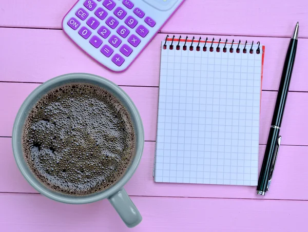Notebook with calculator and coffee cup on purple table