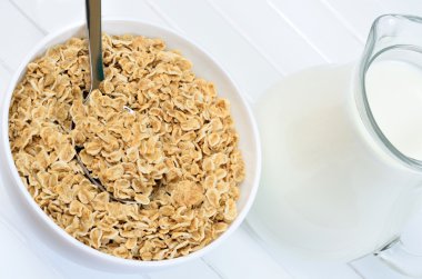 Bir kase yulaf gevreği beyaz ve masanın üzerine süt