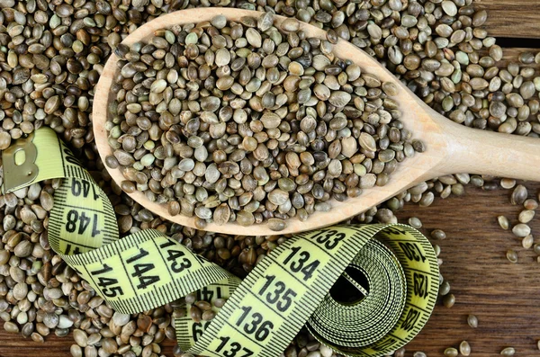 Zdravých konopných semen v dřevěnou lžící s centimetr — Stock fotografie