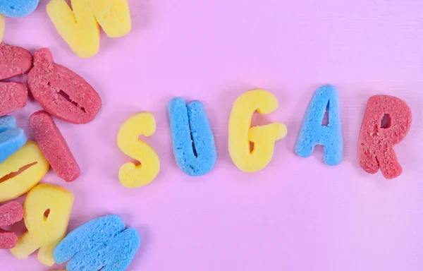 Word Sugar on pink table — Stock Photo, Image