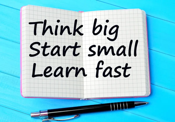 The words Think big Start small Learn fast on notebook