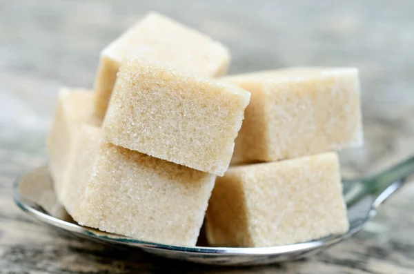 Cubos de azúcar beige en una cuchara de plata — Foto de Stock