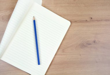 Boş defteri ahşap bir masada kalemle kapat.