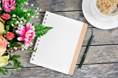 Boş defter, kalem, kahve fincanı ve renkli çiçekler. Üst görünüm