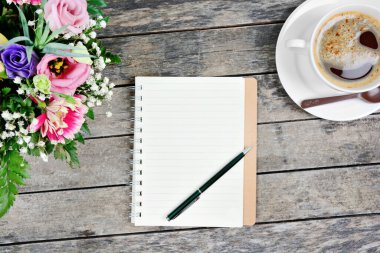 Boş defter, kalem, kahve fincanı ve renkli çiçekler.