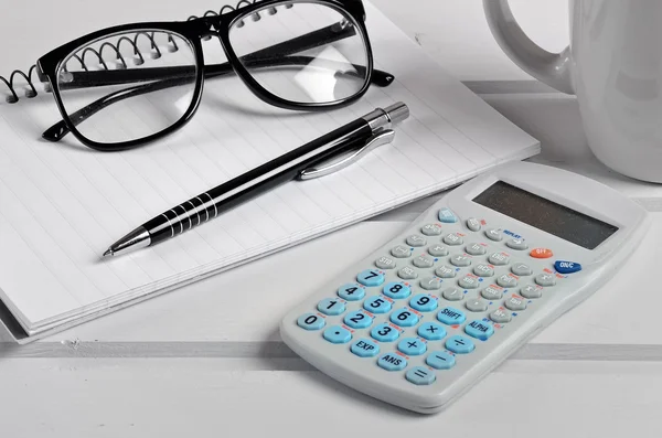 Cuaderno con gafas, calculadora y bolígrafo —  Fotos de Stock