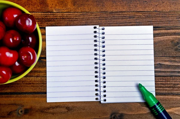 Notebook and green bowl with cherries — ストック写真