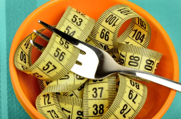 Orange bowl with centimeter and fork — Stock Photo, Image