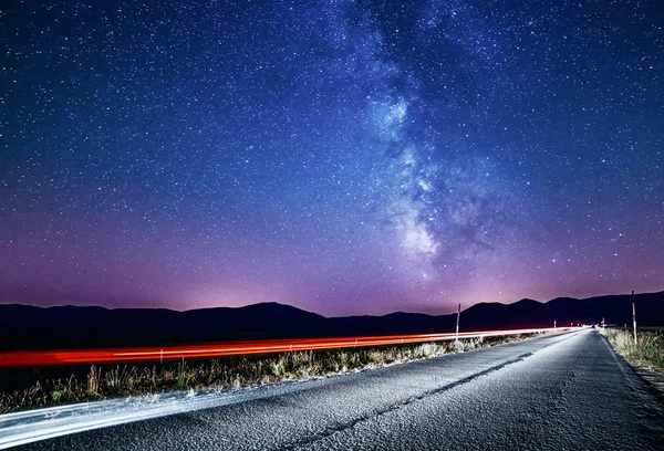 Nachtelijke hemel met de Melkweg en sterren. Nacht weg verlicht door auto — Stockfoto