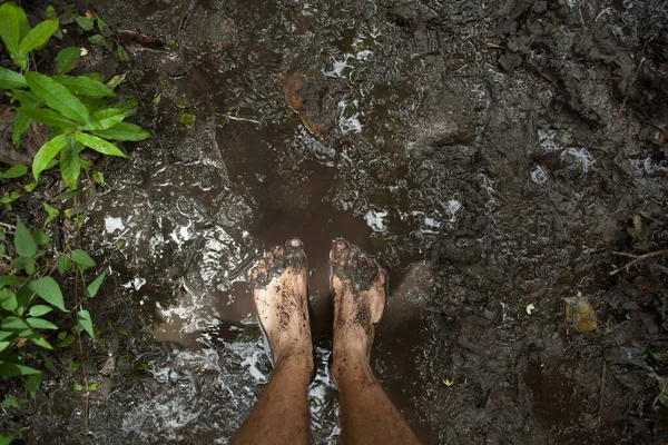 Mans feet in the mud in the jungle of Komodo island