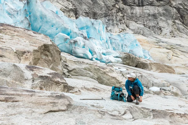 Egy nő beköti a cipőfűzőjét a Jostedal Gleccser túrán. Jostedalsbreen Nemzeti Park, Norvégia. — Stock Fotó