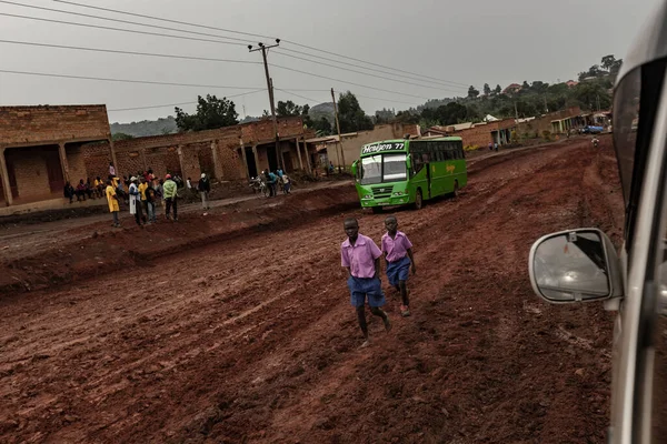School boys walk on a mud road. View from the car window. Uganda — Stock Photo, Image