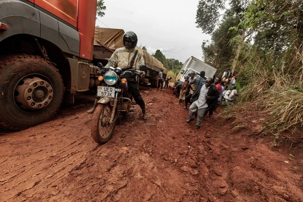 A truck stuck in the mud on a dirt road is helped out by local men. Uganda — Stock Photo, Image