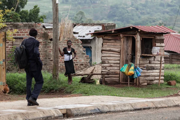 KIBALE NATIONAL PARK, UGANDA - MARCH 15, 2018: An unidentified local girl stands next to her small wooden house on March 15, 2018 in the village near Kibale National Park, Uganda — Stock Photo, Image