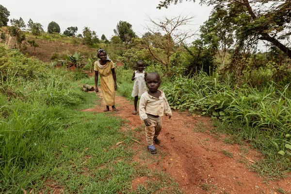 KIBALE NATIONAL PARK, UGANDA - MARCH 15, 2018: An unidentified woman with two children walks on a narrow trail in the jungle on March 15, 2018 in Kibale National Park, Uganda — Stock Photo, Image