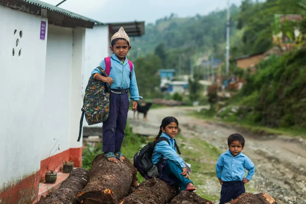 POKHARA, NEPAL - 31 DE MAYO DE 2016: Niños con sus uniformes se sientan en los troncos el 31 de mayo de 2016 en Nepal —  Fotos de Stock