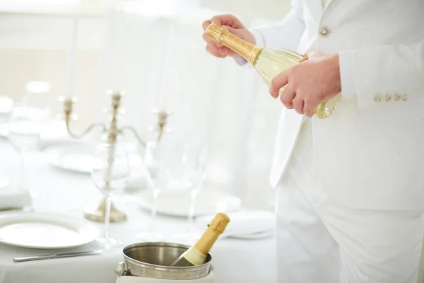 Человек в белом костюме открывает шампанское — стоковое фото