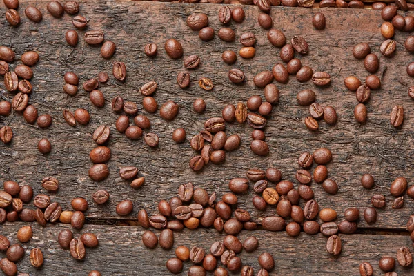 Coffee beans scattered on wooden table — Stock Photo, Image
