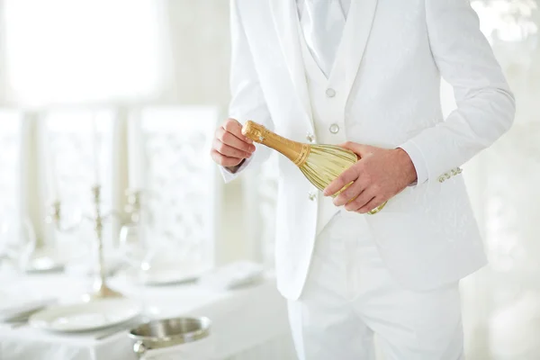 Man in white suit opens champagne — Stock Photo, Image