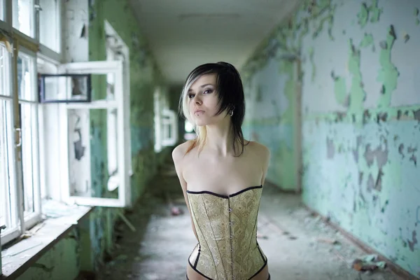 Girl with piercings in corset in corridor — Stock Photo, Image