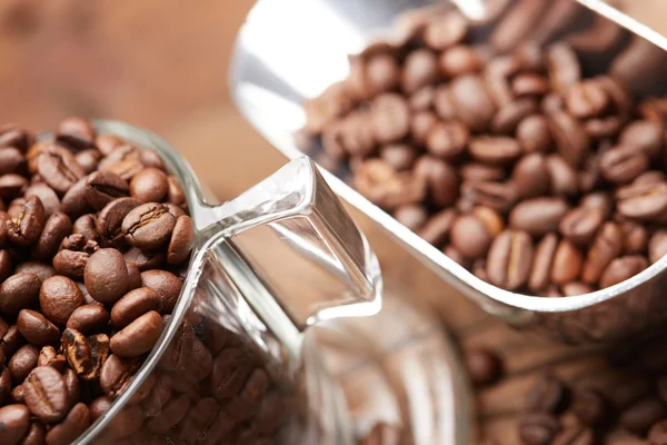 Свежие кофейные зерна в чашке и совок — стоковое фото