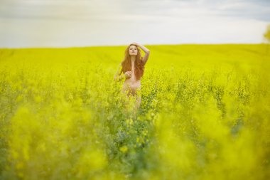 kolza tohumu alanındaki Kızıl saçlı çıplak kız