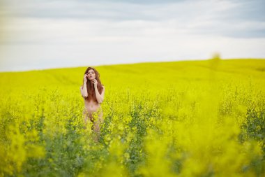 kolza tohumu alanındaki Kızıl saçlı çıplak kız