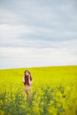 kolza tohumu alanındaki Kızıl saçlı çıplak kız