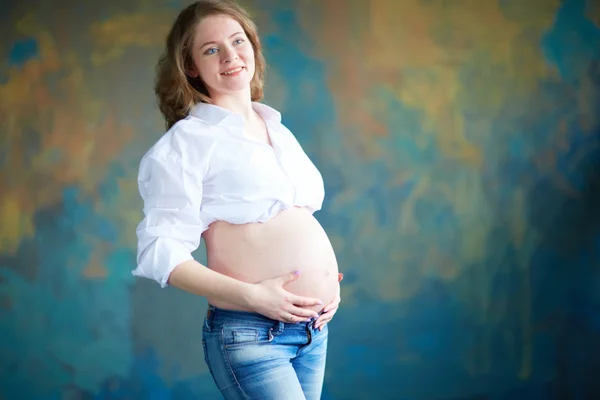 Pregnant woman in jeans in studio Stock Photo