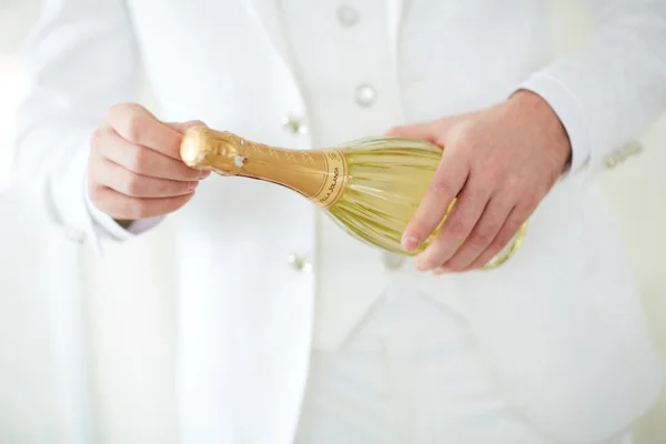 Man in white suit opens champagne — Stock Photo, Image