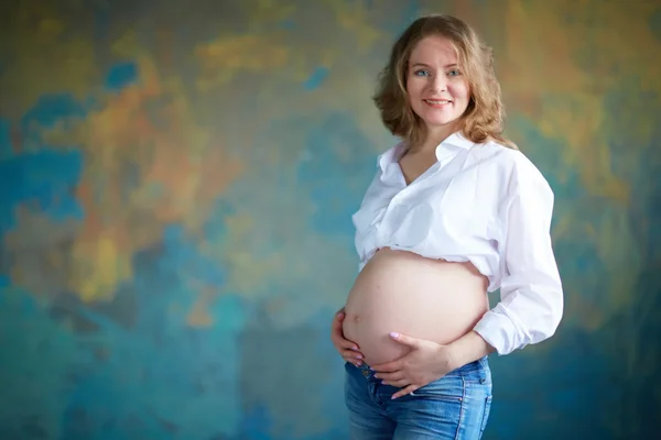 Mulher grávida em jeans no estúdio — Fotografia de Stock