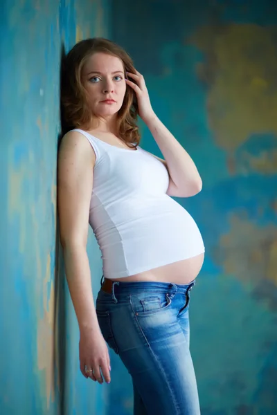 Mulher grávida em jeans no estúdio — Fotografia de Stock