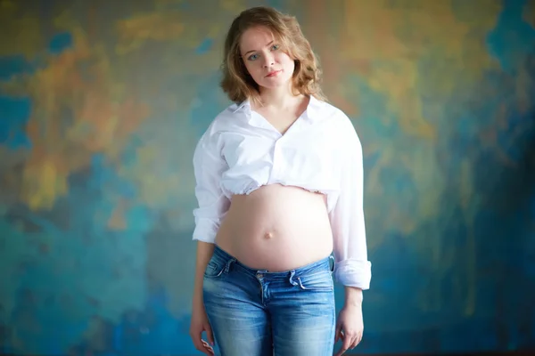 Zwangere vrouw in spijkerbroek in studio — Stockfoto