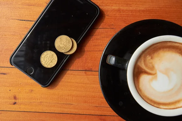 Xícara de café, moedas e telefone — Fotografia de Stock
